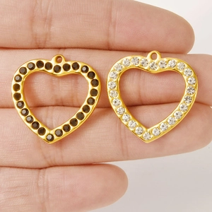 Handheld view of heart-shaped 304 stainless steel pendants with black and clear rhinestones
