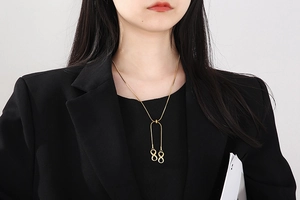 Close-up of a gold-plated snake chain necklace with a vertical double infinity pendant