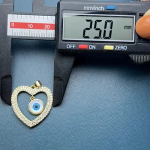 Macro shot of gold heart shell evil eye pendant measuring 25.0mm on a digital caliper