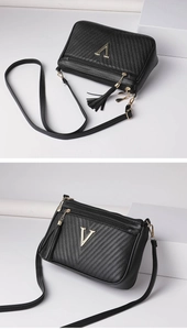 Detailed view of black quilted shoulder bag with golden V logo and hanging tassel charm.