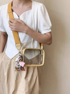 Detail of transparent PVC crossbody bag with yellow trim and colorful silk scarf detail