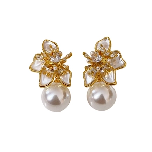 Elegant gold plated floral pearl stud earrings featuring crystal accents on white background