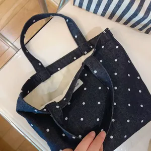 Top view of blue polka dot denim tote bag with white inner lining and dual handles