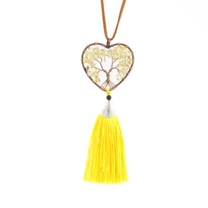 Macro detail of hand-woven tree of life heart pendant with yellow stones and fringe