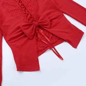 Dettaglio top rosso a maniche lunghe con pizzo, grande fiocco e lacci incrociati