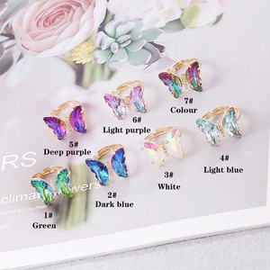 Detalle de anillos de mariposa ajustables en resina con degradado de colores sobre oro