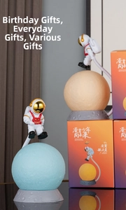 Detail of levitating astronaut moon lamp on crater base with themed gift box packaging