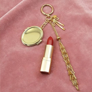 Pink bow metal keychain with photo locket and red lipstick on velvet backdrop