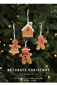 Christmas resin gingerbread man and house ornaments hanging on a warm lit tree