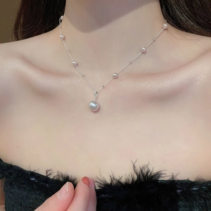 Close-up of a French vintage irregular pearl pendant necklace worn on the collarbone