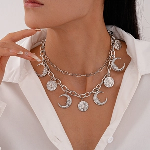 Detail of silver sun and moon layered necklace on a white shirt collar for women