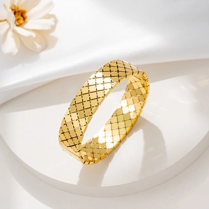 Bracciale rigido in acciaio dorato con motivo a rombi trapuntati su espositore bianco