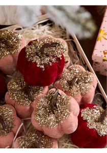 Macro detail of velvet pumpkins with gold sequins and resin stems in a gift box