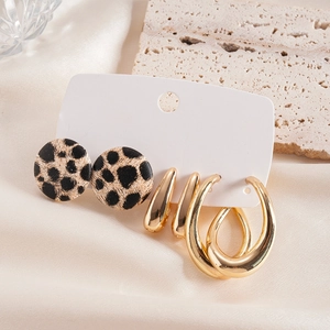 Close-up of gold metal and leopard print earrings set on elegant silk and stone