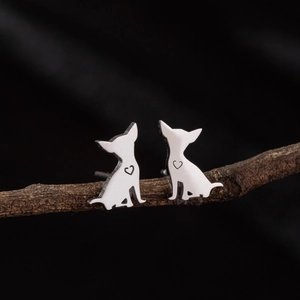 Cute stainless steel dog stud earrings with heart cutout on a minimalist wood branch