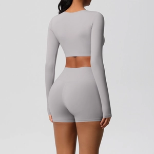 Back view of a grey yoga set featuring a tight long sleeve crop top and high waist shorts