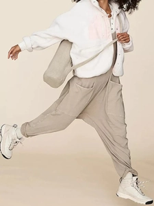 Detail of loose beige overalls with side cargo pockets and white fleece zipper jacket