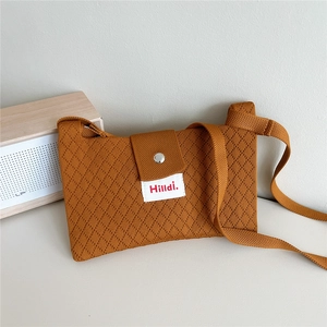 Detail of caramel knit crossbody bag showing diamond weave texture and magnetic button