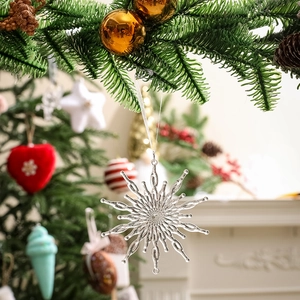 Transparent acrylic snowflake ornament hanging on a green pine branch for Christmas decor