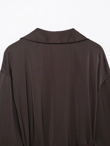 Detail view of the back collar and smooth satin texture of the dark brown shirt
