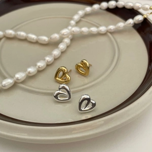 Minimalist gold and silver 925 sterling silver hollow heart earrings on a ceramic plate