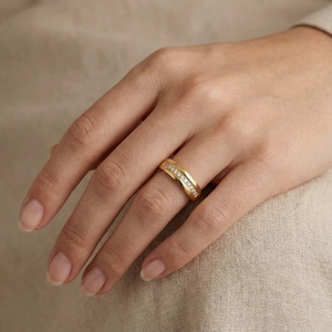 Detail of gold titanium steel ring with micro-pave zircon on a model's hand