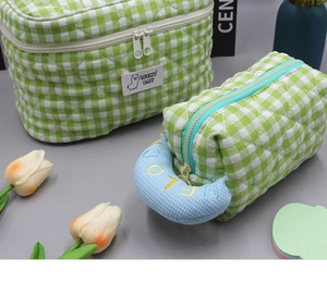 Detail of green checkered quilted makeup bags with LUCKY DAY label and LOVELY embroidery