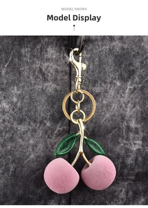 Detail of pink flocked cherry keychain with green glitter leaves and gold hardware
