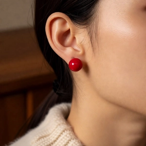 Close-up of elegant red spherical stud earrings worn on model for a vintage French style