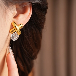 Close-up of vintage gold crossover earrings with clear square-cut zircon stone on model