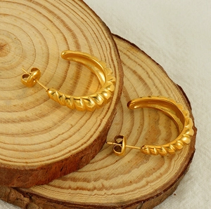 Detail of 18K gold plated hoop earrings with twisted spiral texture on wood background