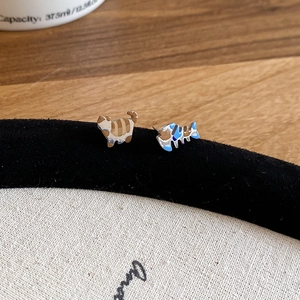 Macro shot of cute asymmetrical cat and fishbone stud earrings on a velvet stand