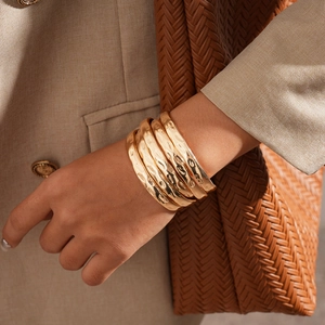 Gros plan détaillé de 5 bracelets dorés avec texture martelée et design géométrique chic