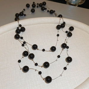 Close-up of double-layered long necklace featuring black beads and silver metal chains