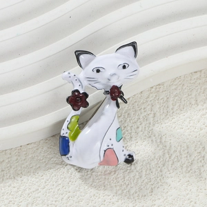 Detailed view of white enamel cat brooch with red flower and colorful spots decoration