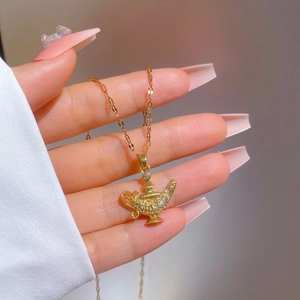 Elegant gold magic lamp necklace with cubic zirconia, held in hand to show fine detail