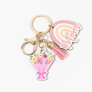 Detail of wooden MOM keychain with pink tassel and rainbow cloud charm on white background