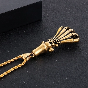 Close-up of golden gothic skull pendant with skeletal wings on a textured background