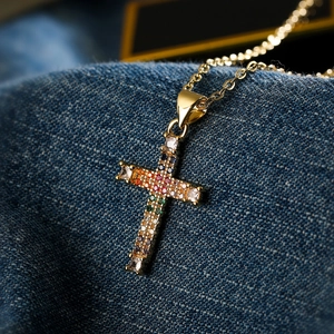 Collana con ciondolo a croce in zirconi arcobaleno e finitura oro su denim blu