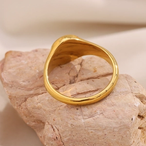 Detailed view of an 18K gold plated stainless steel moon ring on a textured stone base