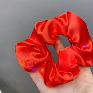 Detail shot of red satin LED scrunchie with colorful lights for party hair styling