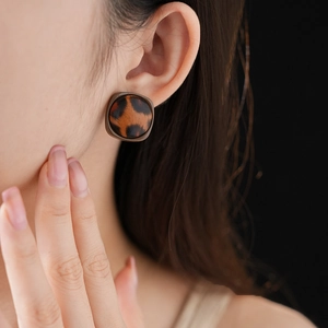 Gros plan d'une femme portant des boucles d'oreilles rondes léopard avec bordure en cuir