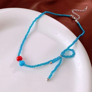 Detail showing blue glass bead necklace with bow design and silver lobster clasp