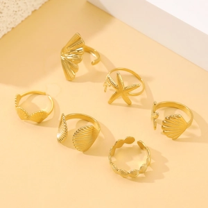 Detail of six-piece golden ocean theme ring set featuring starfish and seashell designs