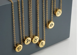 Macro shot of gold stainless steel necklace featuring a round engraved zodiac sign pendant