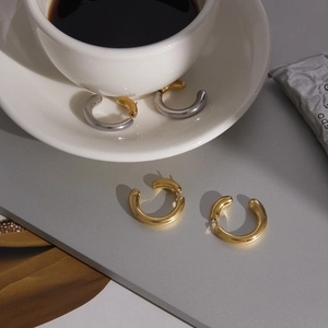 Gros plan de boucles d'oreilles créoles en C minimalistes en or 18 carats et argent