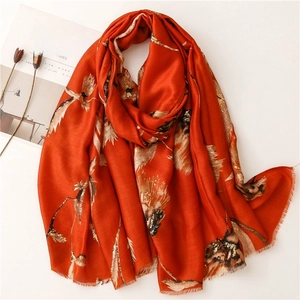 Detail of soft orange linen-feel scarf with gold floral foil print and frayed edges