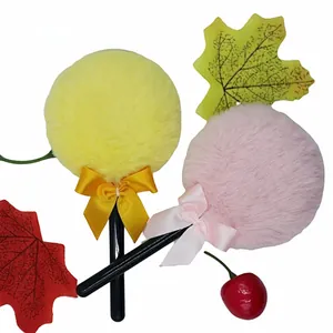 Detail of plush lollipop powder puffs in yellow and pink with satin bow decorations