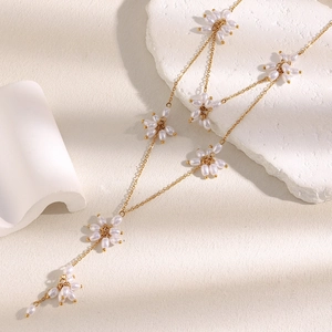 Close-up of 18K gold plated flower necklace with pearls and elegant tassels on stone