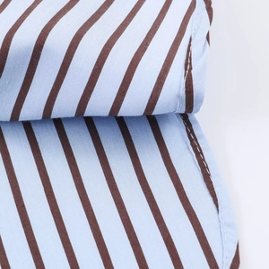 Vue macro montrant les coutures fines et les rayures bleues et brunes sur la popeline